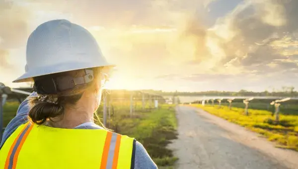 Technicienne faisant face à des panneaux solaires et un couché de soleil
