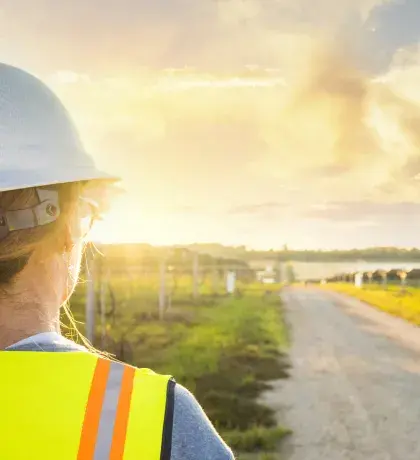 Technicienne faisant face à des panneaux solaires et un couché de soleil