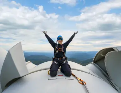 Employée sur le toit d'une éolienne levant les bras