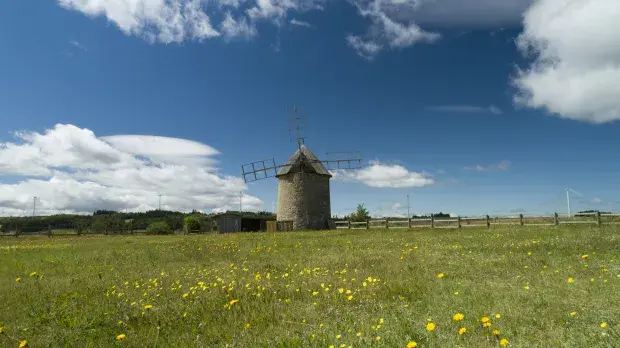 Moulin devant les éoliennes du Plateau d'Ally-Mercoeur en France