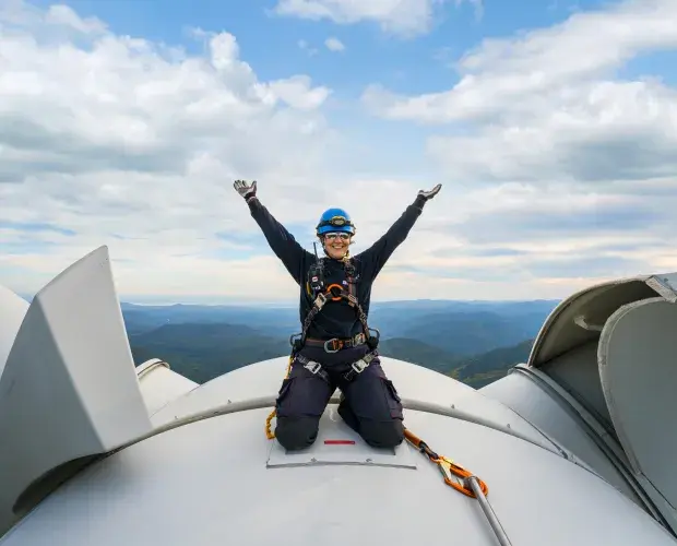 Employée sur le toit d'une éolienne levant les bras